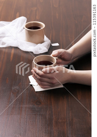Covering a mug of tea bags with both hands 115391163