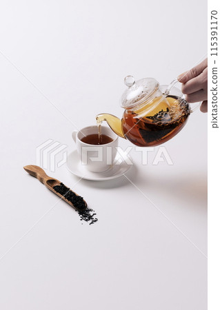 pouring tea from a teapot into a cup 115391170