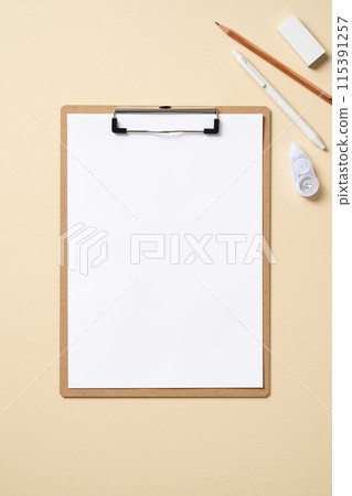 clipboards and writing instruments with a light yellow pastel background 115391257