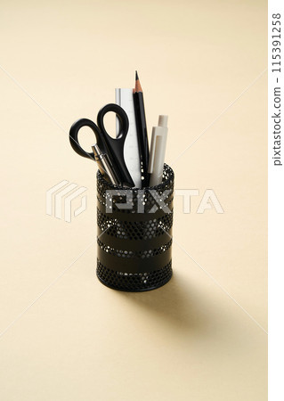 a black pencil holder with a light yellow pastel background 115391258