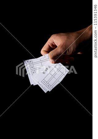 a hand holding several torn ballots 115391346