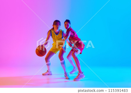 Concentration on victory, Two young women, basketball payers in motion with ball, competing against gradient pink blue background in neon light. Concentration on victory, Two young women, basketball payers in motion with ball, competing against gradient pink blue background in neon light. 115391483