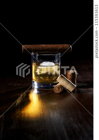 composition of a glass of whiskey with ice, cigar cigarette, and rock plug 115391613