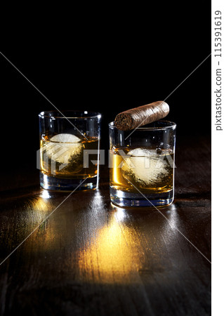 the composition of a glass of whiskey and cigar cigarettes with ice 115391619