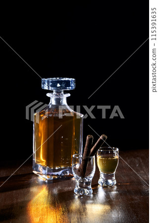 a bottle of liquor and glasses with a black background 115391635