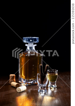 a bottle of liquor and glasses with a black background 115391638
