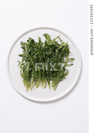a pile of rucola on a white plate 115391945