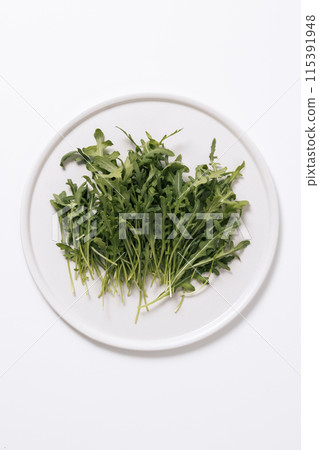 a pile of rucola on a white plate 115391948