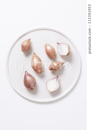 several shallots on a white plate 115391953