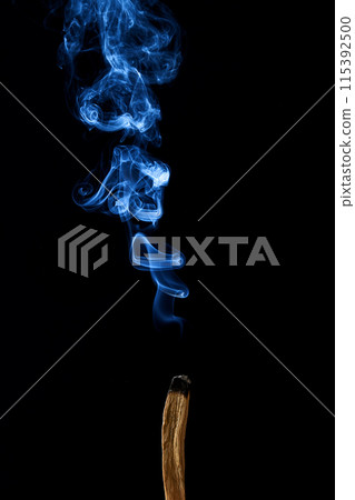 Smudge stick with smoke against a dark background 115392500