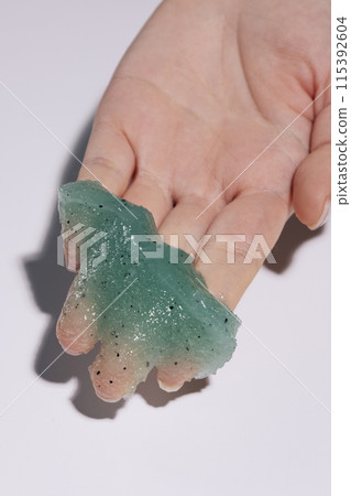 A soft, teal scrub on the palm of your hand 115392604