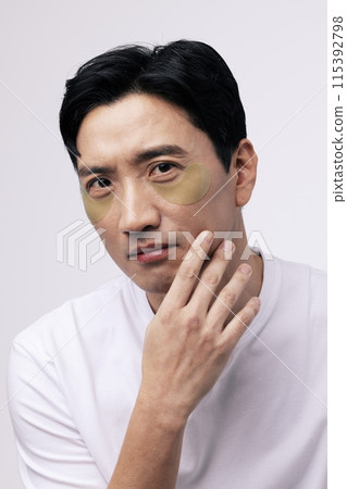 a middle aged man staring straight ahead with eye patches around his eyes 115392798
