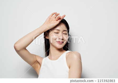 Asian Woman Poses With Her Eyes Closed and Her Hands On Her Head Asian Woman Poses With Her Eyes Closed and Her Hands On Her Head 115392863