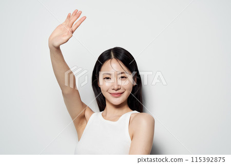 Asian woman posing with one hand against a white background Asian woman posing with one hand against a white background 115392875