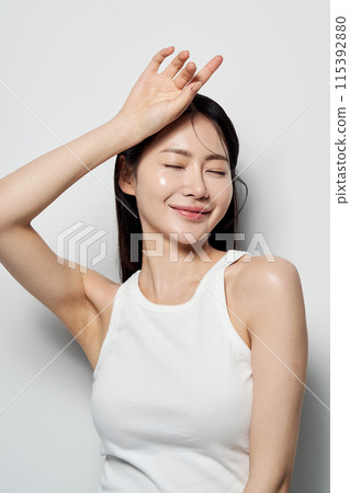 Asian Woman Poses With Her Eyes Closed and Her Hands On Her Head 115392880