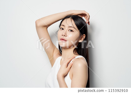 an Asian woman staring straight ahead with her hands on her head 115392910
