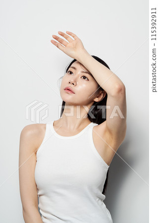 an Asian woman with her hands on her forehead staring into the distance 115392911