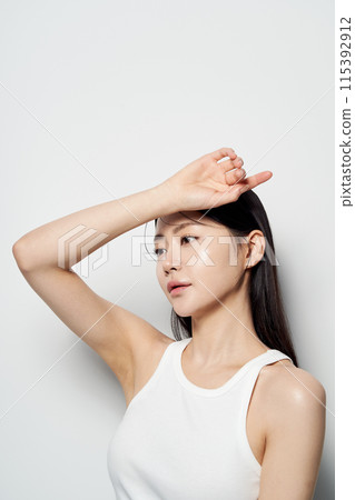 an Asian woman with her hands on her forehead staring into one spot 115392912