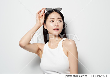 an Asian woman staring sideways in sunglasses with one hand 115392921