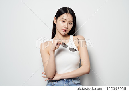 an Asian woman smiles while taking off her sunglasses an Asian woman smiles while taking off her sunglasses 115392936