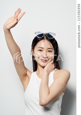 an Asian woman who smiles with her hands up and sunglasses on 115392956
