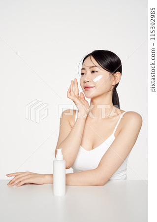 Asian Woman Poses to Apply Cosmetics to Her Face Asian Woman Poses to Apply Cosmetics to Her Face 115392985
