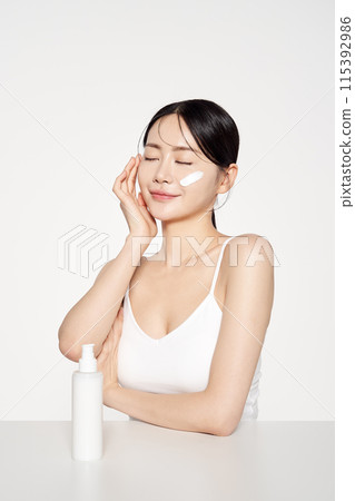 Asian Woman Poses to Apply Cosmetics to Her Face 115392986