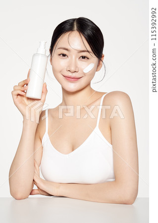 Asian Woman Stares Front With Cosmetics Bottle 115392992