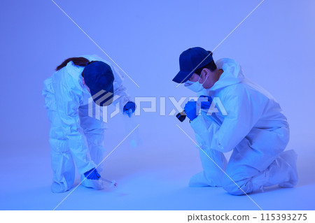 CSI Scientific Investigation Unit male and female researchers identifying and collecting evidence at crime and incident sites with blue lights 115393275