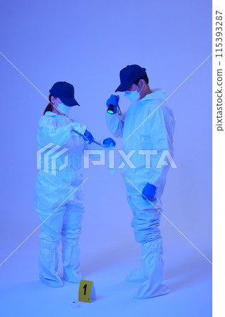 CSI Scientific Investigation Unit male and female researchers identifying and collecting evidence at crime and incident sites with blue lights CSI Scientific Investigation Unit male and female researchers identifying and collecting evidence at crime and incident sites with blue lights 115393287
