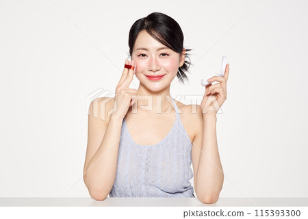 an Asian woman who applies cushion compacts to her face an Asian woman who applies cushion compacts to her face 115393300