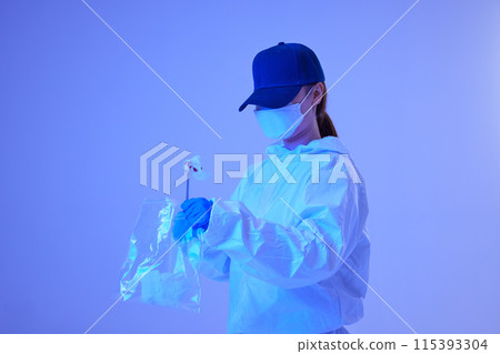 CSI female researcher collecting evidence in envelopes at crime and incident sites with blue lights 115393304