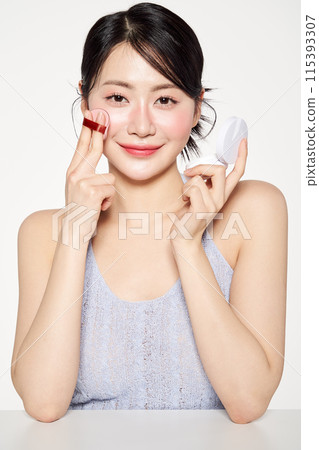 an Asian woman who applies cushion compacts to her face an Asian woman who applies cushion compacts to her face 115393307