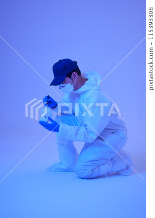 CSI Scientific Investigation Unit male researcher fingerprinting cups at crime and incident sites with blue lights 115393308