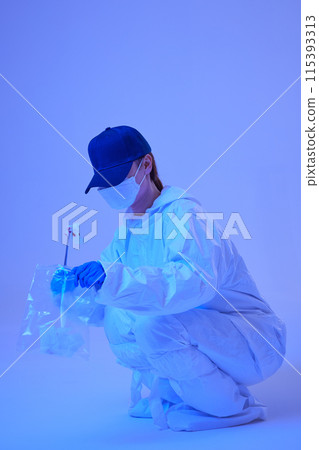 CSI female researcher sitting at crime and incident sites with blue lights collecting evidence in envelopes CSI female researcher sitting at crime and incident sites with blue lights collecting evidence in envelopes 115393313