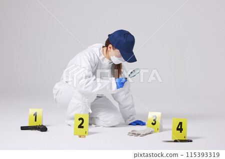 Evidence Marker A female researcher who checks evidence with a magnifying glass at the crime scene and at the incident site Evidence Marker A female researcher who checks evidence with a magnifying glass at the crime scene and at the incident site 115393319