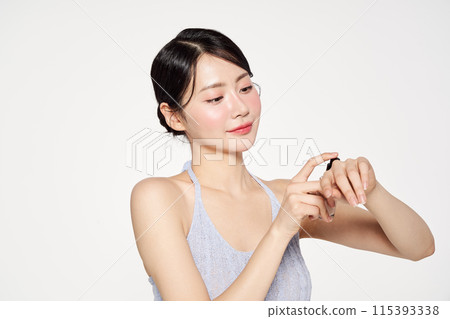 an Asian woman who applies foundation on the back of her hand an Asian woman who applies foundation on the back of her hand 115393338