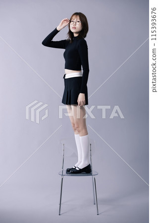 A Korean woman in her 20s who sits on a chair and touches the frame with one hand 115393676