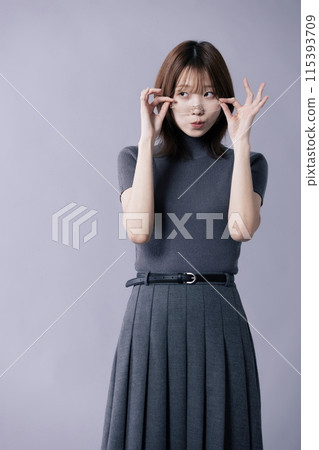 A Korean woman in her 20s who wears a gray costume and touches glasses frames with both hands A Korean woman in her 20s who wears a gray costume and touches glasses frames with both hands 115393709