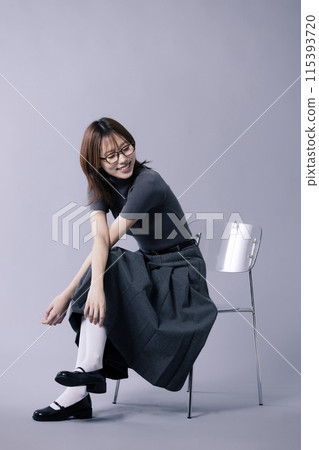 A Korean woman in her 20s who wears a geek look style and smiles sitting on a chair A Korean woman in her 20s who wears a geek look style and smiles sitting on a chair 115393720