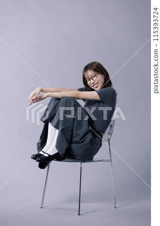 A Korean woman in her 20s who wears a geek look style and sits on a chair, closes her eyes and smiles A Korean woman in her 20s who wears a geek look style and sits on a chair, closes her eyes and smiles 115393724
