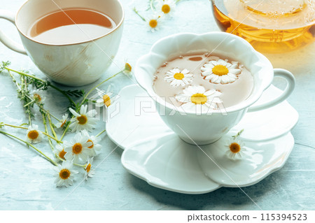 Chamomile flower tea. A tea cup and a tea pot with fresh medicinal flowers 115394523