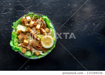Caesar salad with chicken breast, lettuce, croutons, and a lemon Caesar salad with chicken breast, lettuce, croutons, and a lemon 115394530