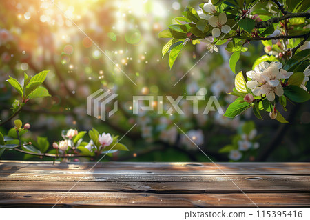 Spring background with green lush young foliage and flowering branches and empty wooden table outdoors 115395416