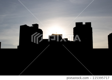 City skyline silhouette with sun shining through clouds 115395717