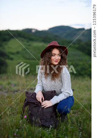 Young tourist woman traveller with backpack walking in nature. Active hiker on trail in mountains enjoying sunset. 115396179
