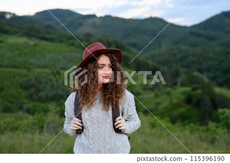 Young tourist woman traveller with backpack walking in nature. Active hiker on trail in mountains enjoying sunset. 115396190