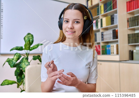 Webcam view of teenage girl, high school student, in headphones, talking to camera 115396485