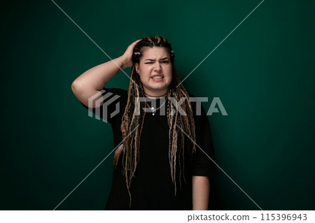 Woman With Dreadlocks Standing in Front of a Green Wall 115396943