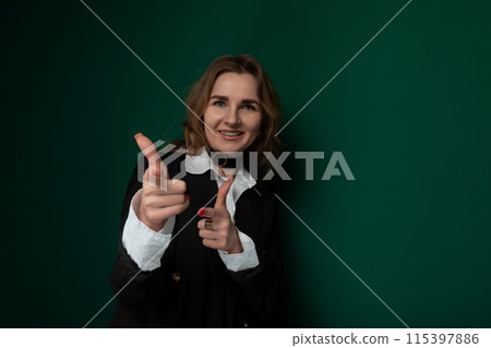 Woman Giving Thumbs Up in Front of Green Wall 115397886